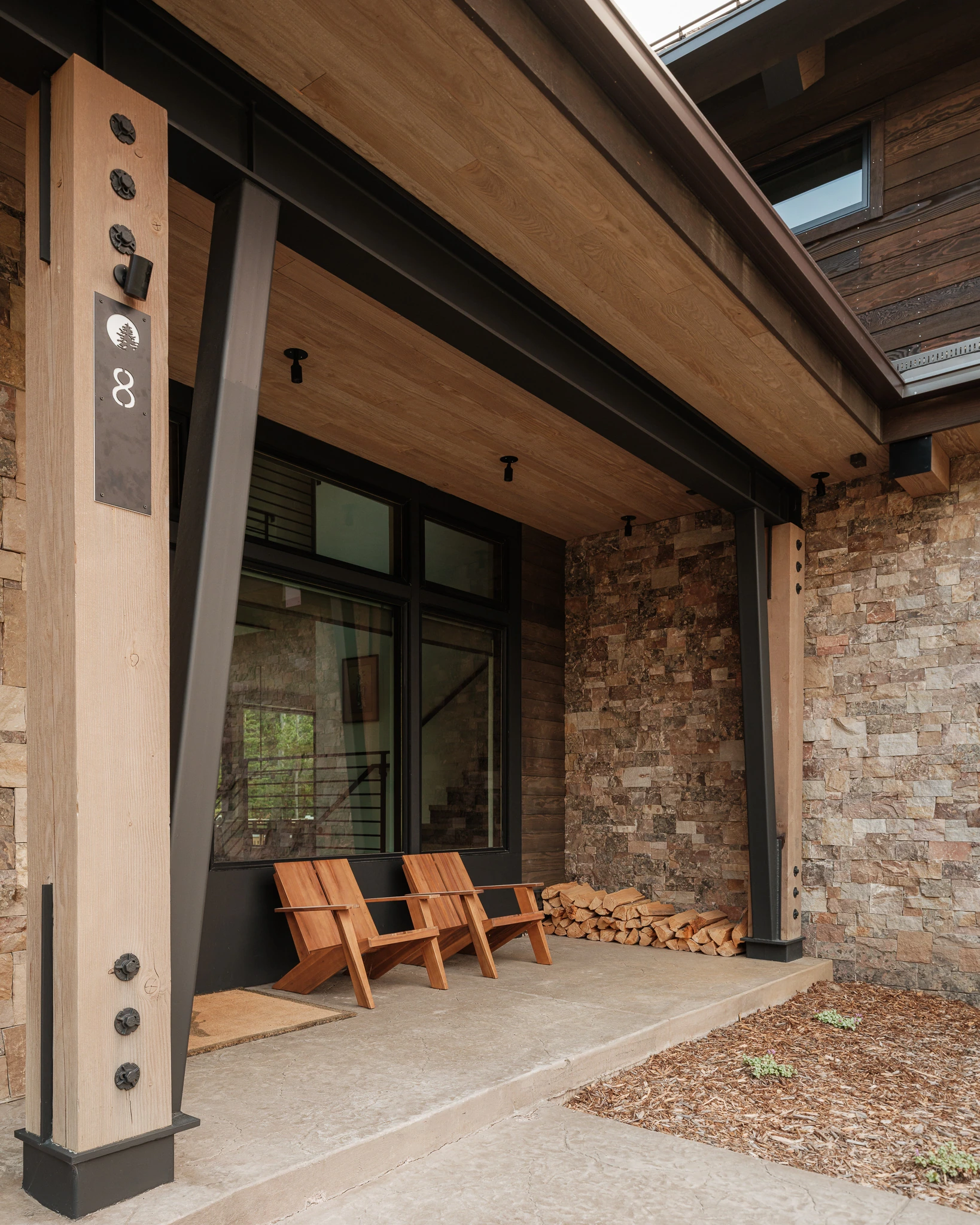 Covered entry porch with stacked stone and Adirondack chairs — architectural photography Big Sky Montana, Reid Smith Architects